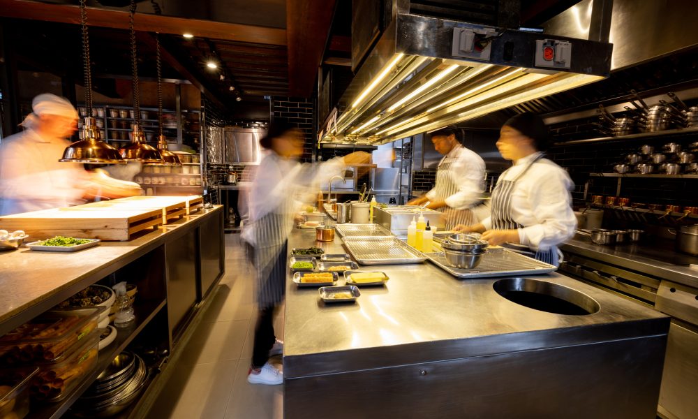 Hectic cooks working in a busy commercial kitchen at a restaurant - food and drink establishment concepts