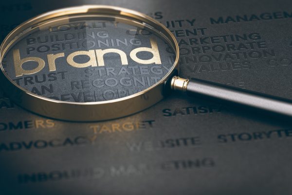Brand marketing and management, branding or rebranding concept. 3d illustration of a magnifying glass over golden and black words.