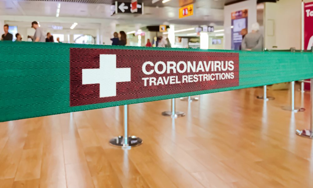 Green ribbon barrier inside an airport with the warning of travel restrictions due to the spread of the dangerous Coronavirus