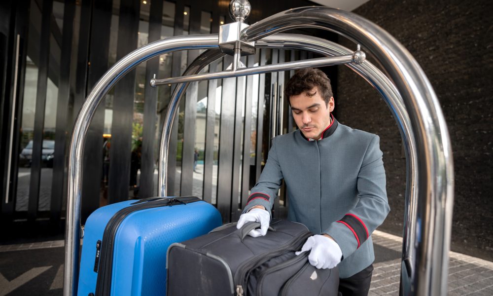 Focused male bellhop placing bags on luggage cart for a guest check in