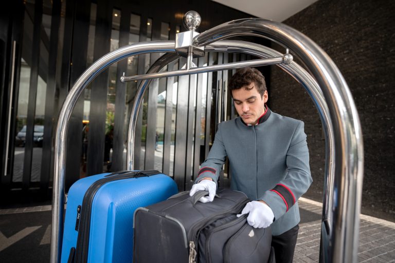 Focused male bellhop placing bags on luggage cart for a guest check in