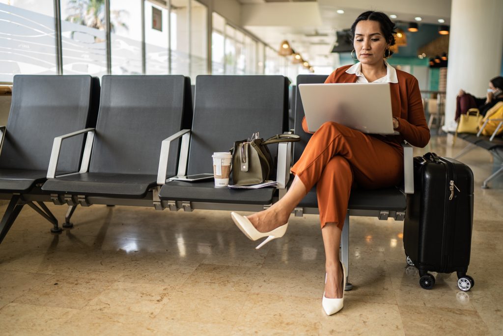 Businesswoman using laptop in the departure area at airport