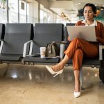 Businesswoman using laptop in the departure area at airport