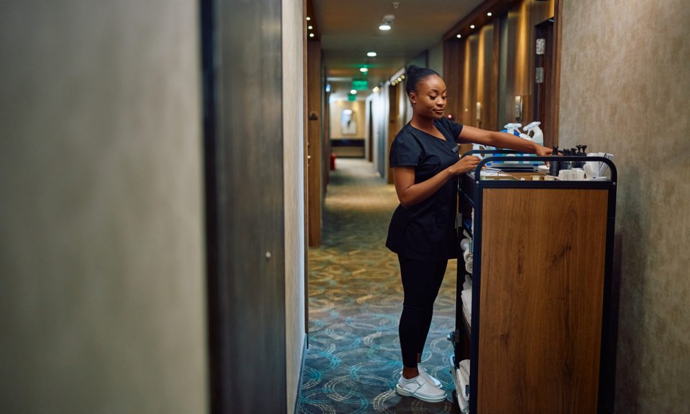 Black female housekeeper replenishing toiletries in guest rooms in a hotel