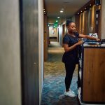 Black female housekeeper replenishing toiletries in guest rooms in a hotel