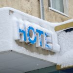 Hotel entrance sign covered in fresh snow after heavy snowfall winter scenery - HospitalityLawyer.com®